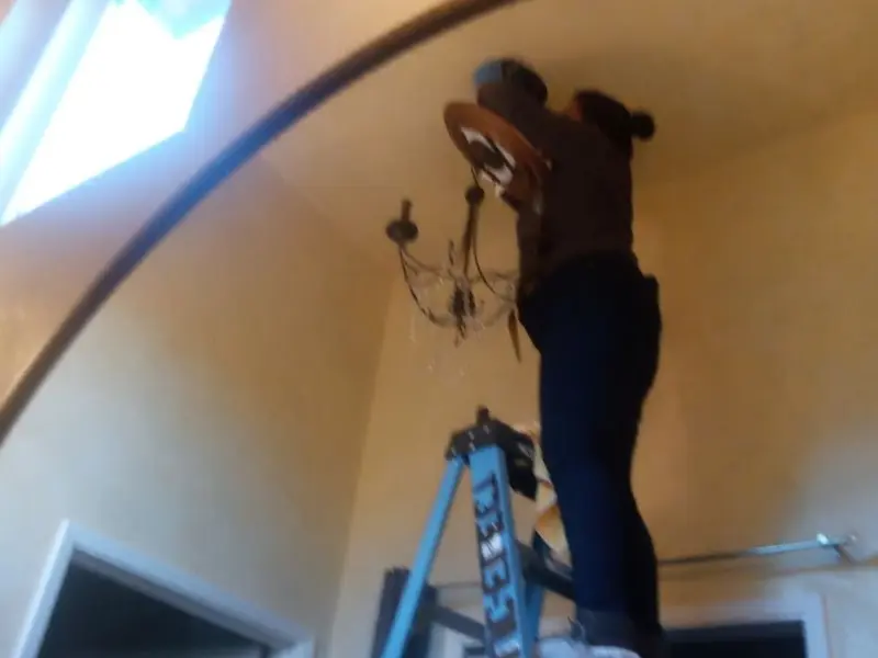 Electrician installing a chandelier in a Hillside residence